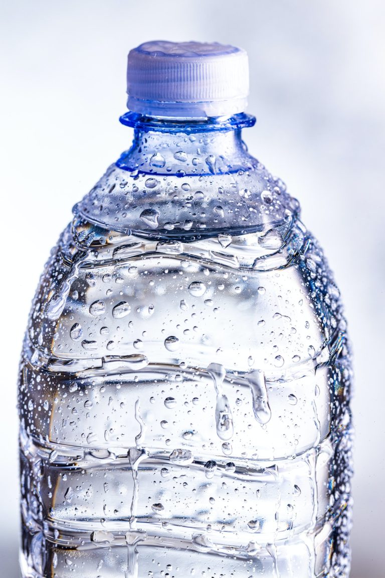 Detail of plastic cold bottle of water with water drops.